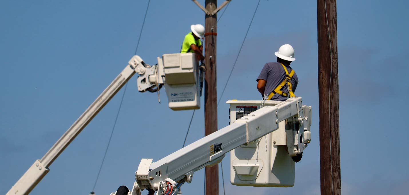 Two aerial linemen coordinate the hanging of fiber across a highway in Eastern Texas.