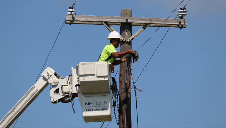 Aerial Lineman lashes fiber optic cable between utility poles
