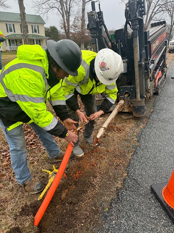 A National crew unhooks conduit from the bore head of a horizontal directional drill in preparation to bury fiber optic cable.